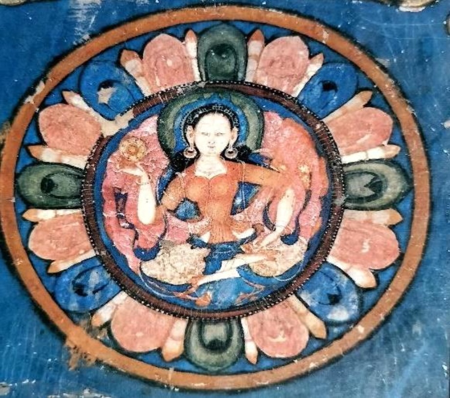 Hình 2 - Sumtsek: Trong mandala Ngũ Phật hình tướng nữ, bố cục chín ô vuông, có một nữ thần màu trắng ngồi ở góc đông nam. Tư thế kiết già kim cang (Vajraparyaṅka), tay phải nâng ấn Chuyển pháp luân (Dharmacakra), tay trái đặt trên đùi, lòng bàn tay hướng lên. Phần trên mặc y phục đỏ tay lửng. Pal xác nhận đây là Locanā. Hình 2 - Sumtsek: Trong mandala Ngũ Phật hình tướng nữ, bố cục chín ô vuông, có một nữ thần màu trắng ngồi ở góc đông nam. Tư thế kiết già kim cang (Vajraparyaṅka), tay phải nâng ấn Chuyển pháp luân (Dharmacakra), tay trái đặt trên đùi, lòng bàn tay hướng lên. Phần trên mặc y phục đỏ tay lửng. Pal xác nhận đây là Locanā.