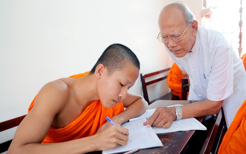 C&ocirc;́ nhà giáo nh&acirc;n d&acirc;n L&acirc;m Es đang hướng d&acirc;̃n các vị sư học chữ Khmer