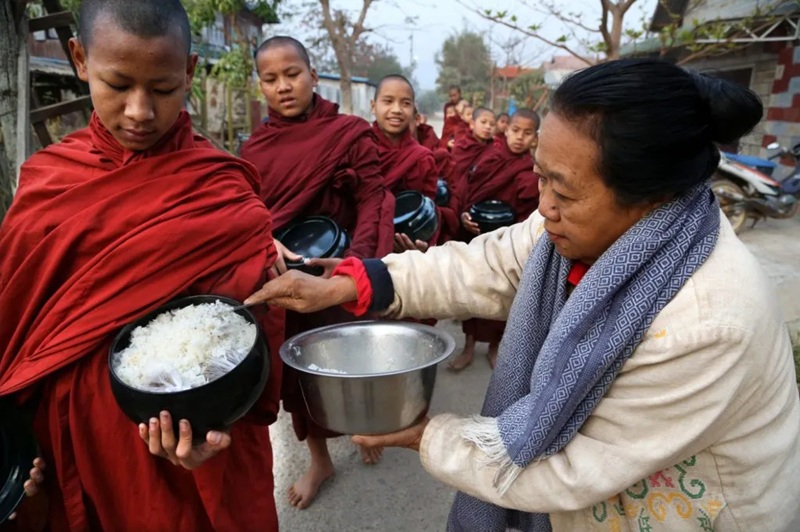 Một nữ phật tử Myanmar c&uacute;ng dường cơm cho c&aacute;c ch&uacute; tiểu trong buổi khất thực hằng ng&agrave;y. (Ảnh: Pascal Mannaerts / Alamy Stock Photo).

